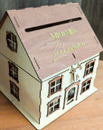 Wooden house-shaped box with 'Mr & Mrs' on the roof, placed on a wooden surface.