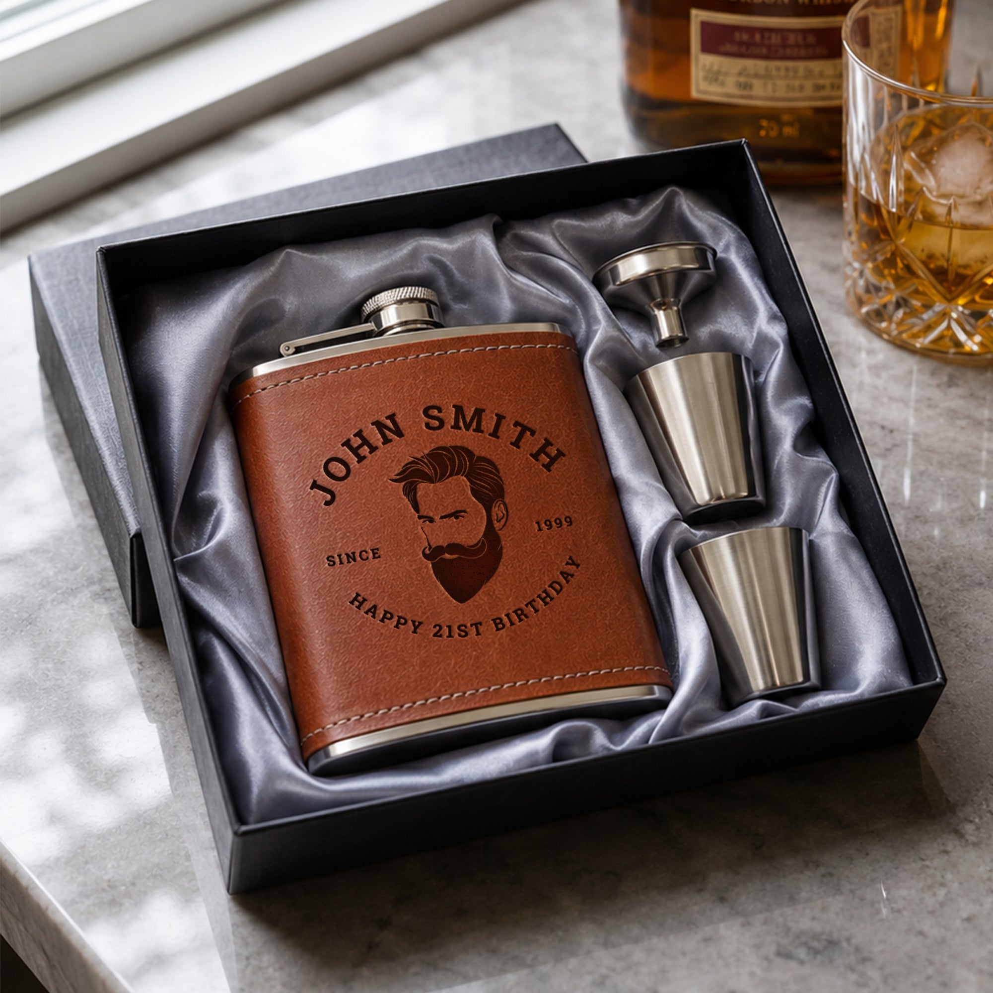 Brown leather flask with engraved text and two metal shot glasses in a black box on a marble surface7oz hip flask gift set, personalised in Australia with name or logo Great for groomsmen, dad birthday