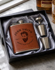 Brown leather flask with engraved text and two metal shot glasses in a black box on a marble surface7oz hip flask gift set, personalised in Australia with name or logo Great for groomsmen, dad birthday