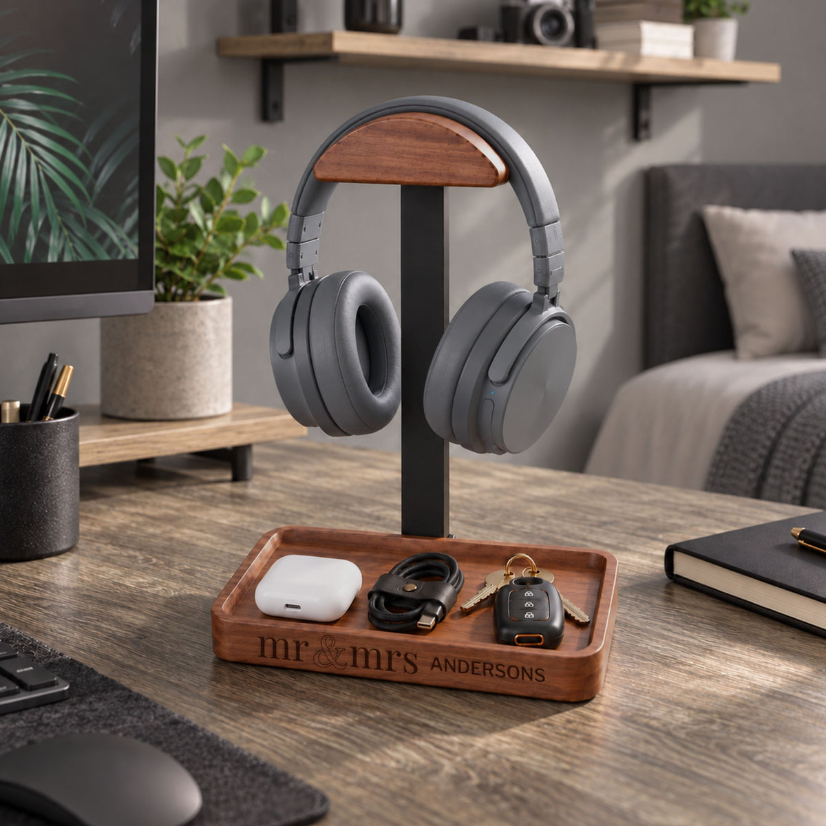 Personalised walnut and metal headphone stand on a desk with headphones and tray holding keys and cable