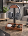 Personalised walnut and metal headphone stand on a desk with headphones and tray holding keys and cable